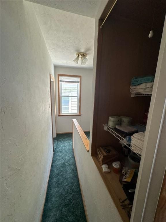 corridor featuring dark colored carpet and a textured ceiling