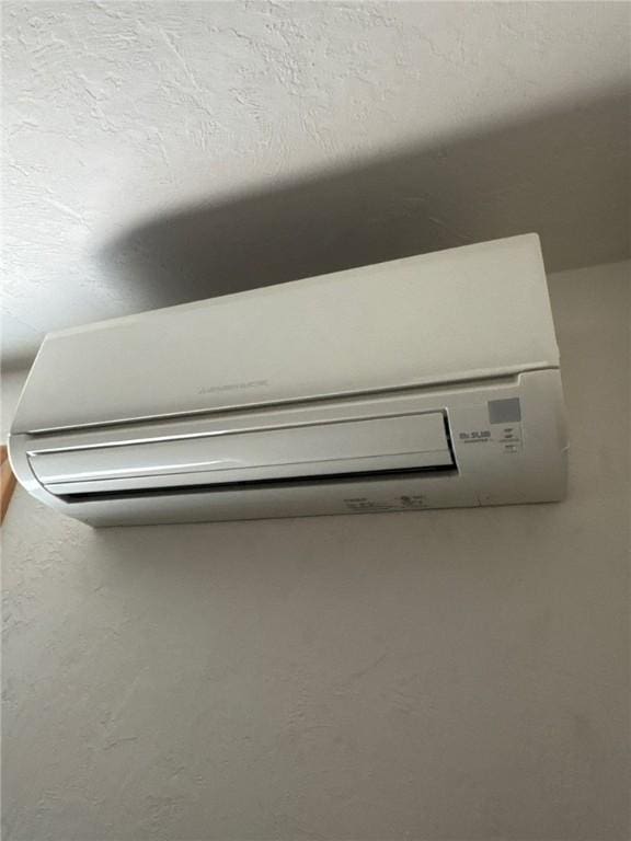 interior details with an AC wall unit and a textured ceiling