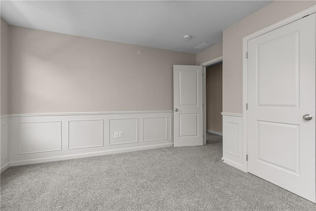 unfurnished bedroom featuring carpet floors and wainscoting