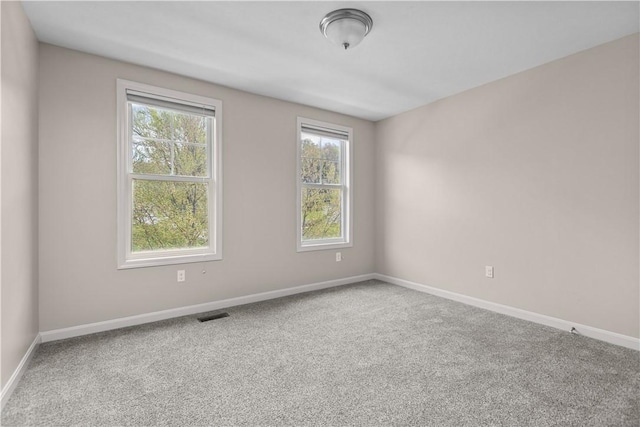 spare room with baseboards, carpet, and visible vents