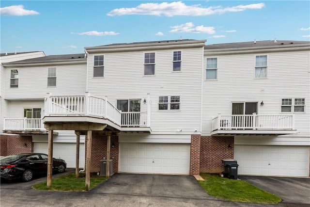 back of property with brick siding, a garage, and aphalt driveway