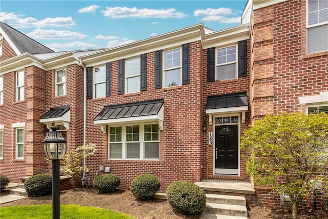 townhome / multi-family property featuring brick siding and a standing seam roof