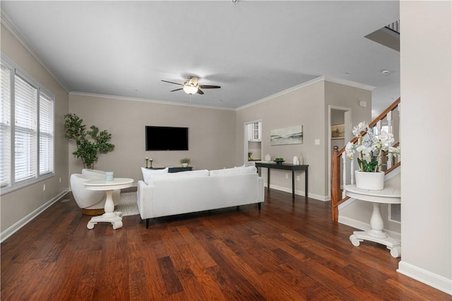 living area with baseboards, ornamental molding, a ceiling fan, and wood finished floors