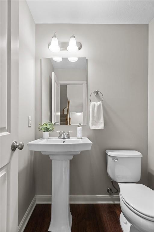 bathroom featuring a sink, baseboards, toilet, and wood finished floors