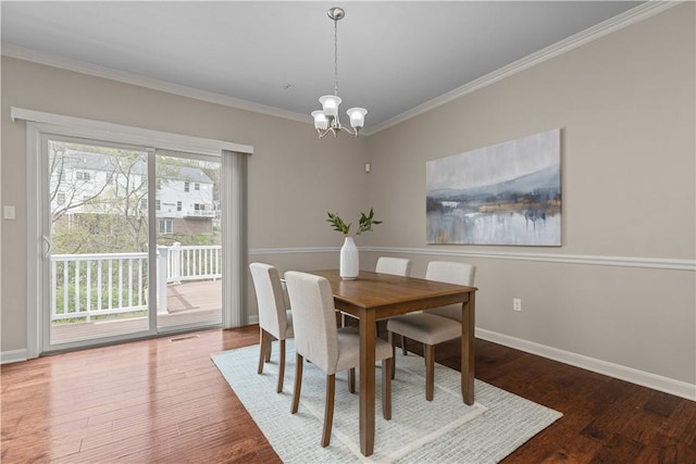 dining area featuring an inviting chandelier, ornamental molding, baseboards, and wood finished floors