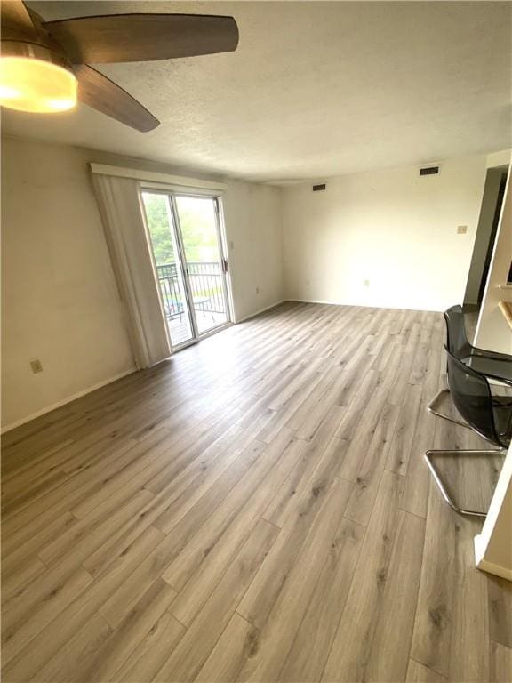 unfurnished living room with visible vents, ceiling fan, and wood finished floors