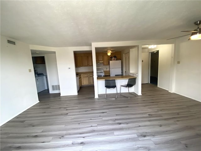 unfurnished living room with visible vents, a ceiling fan, baseboards, and wood finished floors