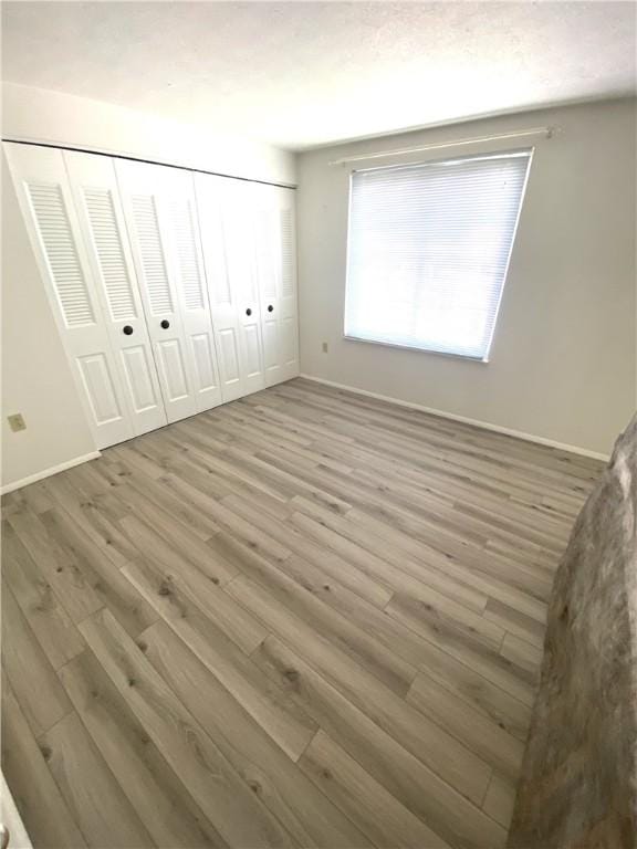 unfurnished bedroom with a closet, baseboards, and wood finished floors
