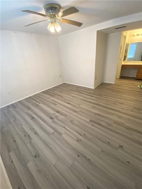 spare room with baseboards, ceiling fan, visible vents, and wood finished floors