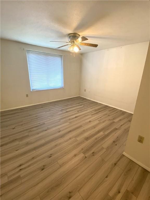 empty room featuring baseboards, a ceiling fan, and wood finished floors