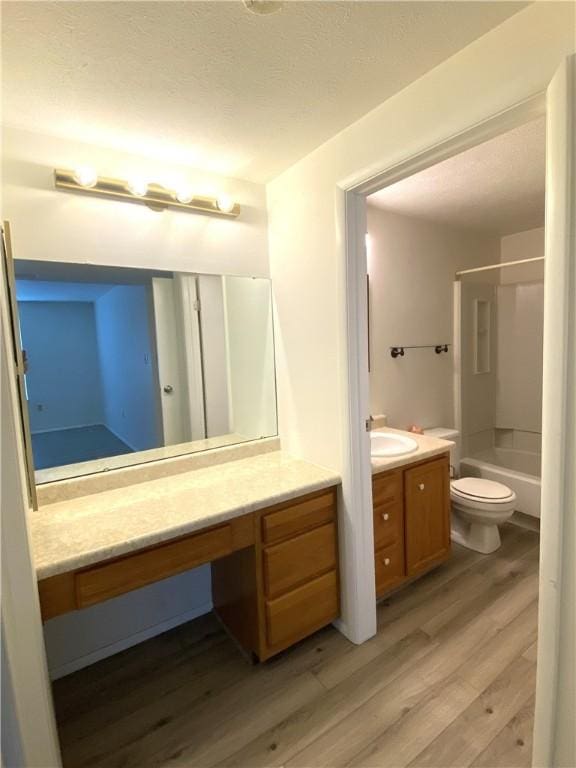 bathroom featuring shower / bathing tub combination, a textured ceiling, wood finished floors, vanity, and toilet