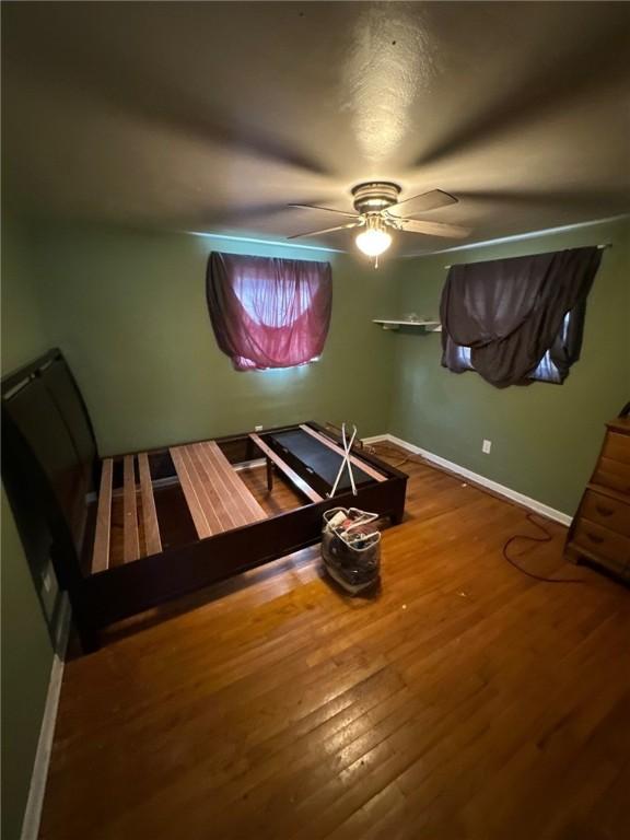 bedroom with baseboards, ceiling fan, and wood finished floors