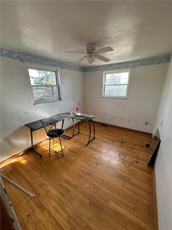 interior space with baseboards, ceiling fan, and wood-type flooring
