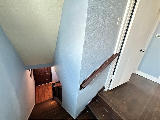 stairway with a textured wall and wood finished floors