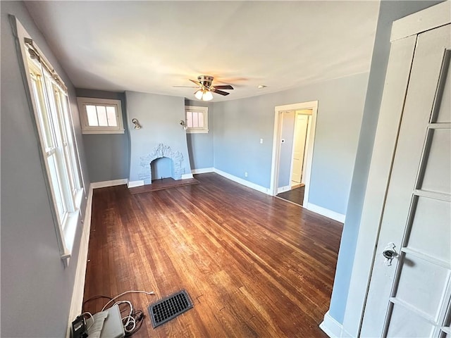 unfurnished living room featuring baseboards, ceiling fan, wood finished floors, and visible vents
