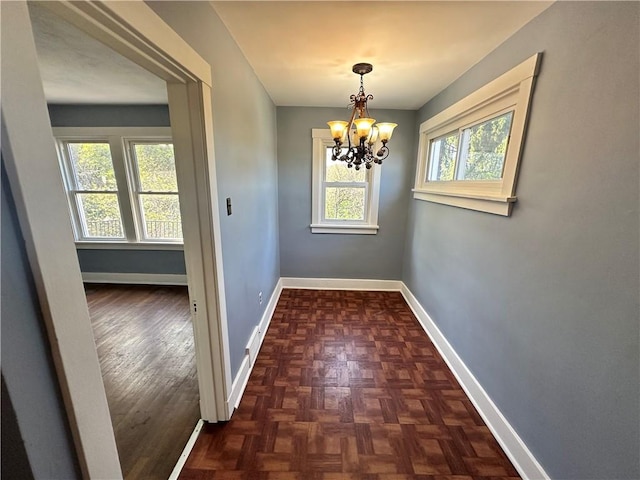 unfurnished dining area with baseboards, an inviting chandelier, and plenty of natural light