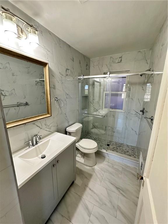 bathroom with vanity, toilet, a marble finish shower, and marble finish floor