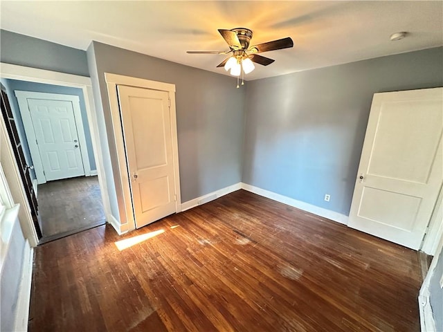 unfurnished bedroom with baseboards, ceiling fan, dark wood-style floors, and a closet