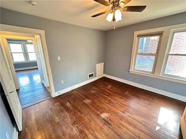 empty room featuring baseboards, visible vents, and dark wood-style floors