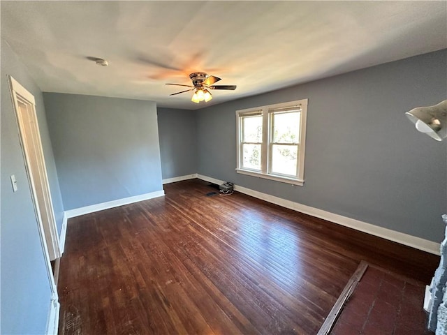 unfurnished room with ceiling fan, dark wood finished floors, and baseboards
