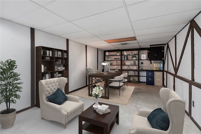 living area featuring concrete floors and a paneled ceiling