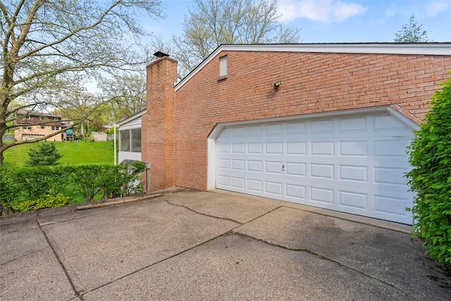 view of side of property with brick siding, a garage, a sunroom, a chimney, and concrete driveway