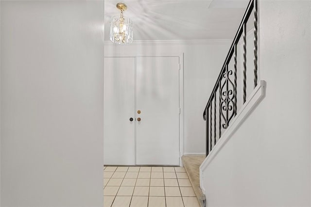 foyer entrance featuring stairway, light tile patterned floors, an inviting chandelier, and ornamental molding