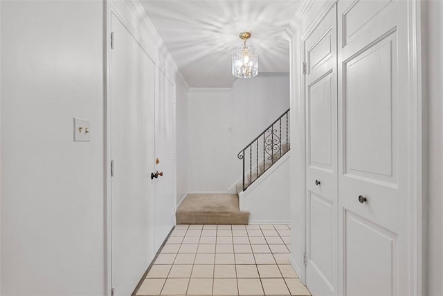 foyer entrance featuring a notable chandelier, ornamental molding, light tile patterned floors, and stairway