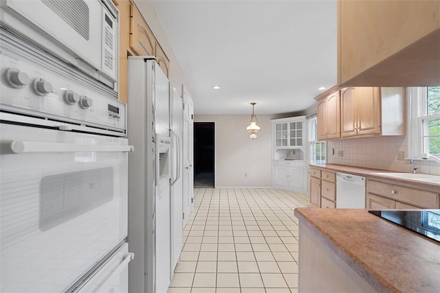 kitchen with white appliances, baseboards, light tile patterned floors, and light brown cabinets