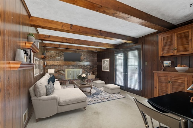 living room featuring carpet flooring, a fireplace, wood walls, and beamed ceiling