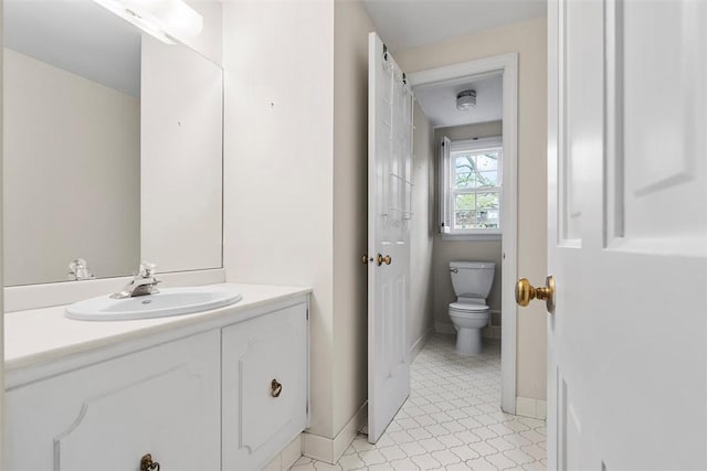 bathroom with toilet, baseboards, and vanity
