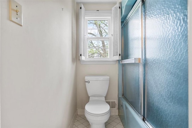 full bath with toilet, baseboards, and shower / bath combination with glass door