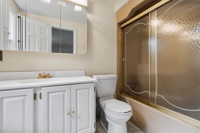 bathroom featuring toilet, combined bath / shower with glass door, tile patterned flooring, and vanity