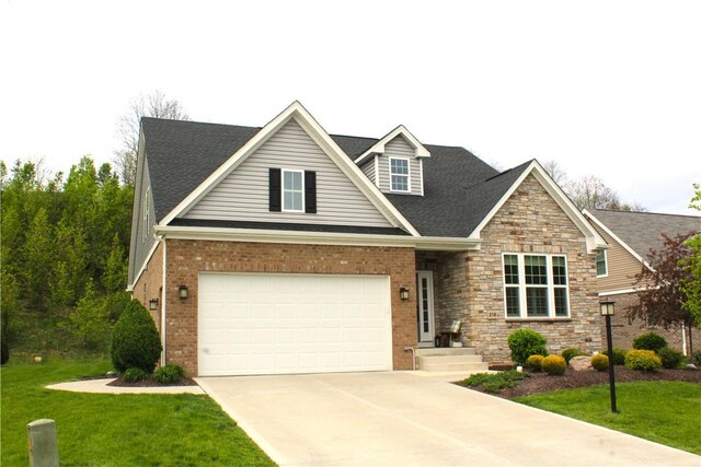 craftsman-style home with brick siding, a shingled roof, a front lawn, and concrete driveway