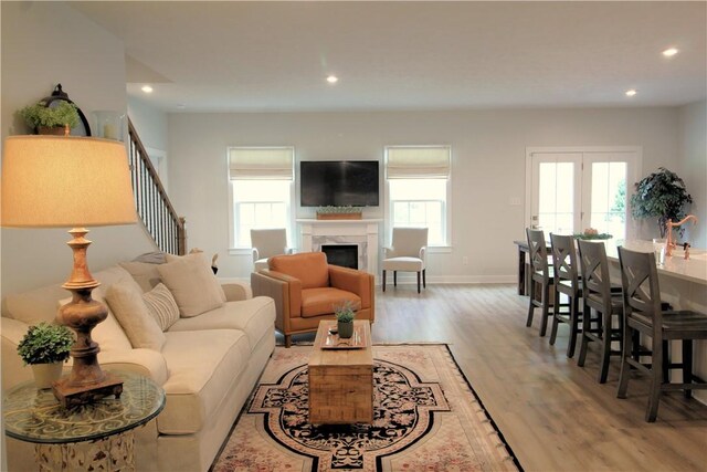 living room with a fireplace, light wood-type flooring, stairs, baseboards, and recessed lighting