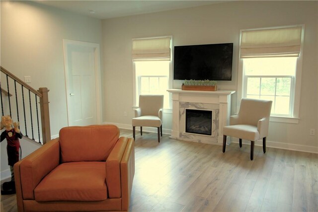 living area with stairs, baseboards, wood finished floors, and a fireplace
