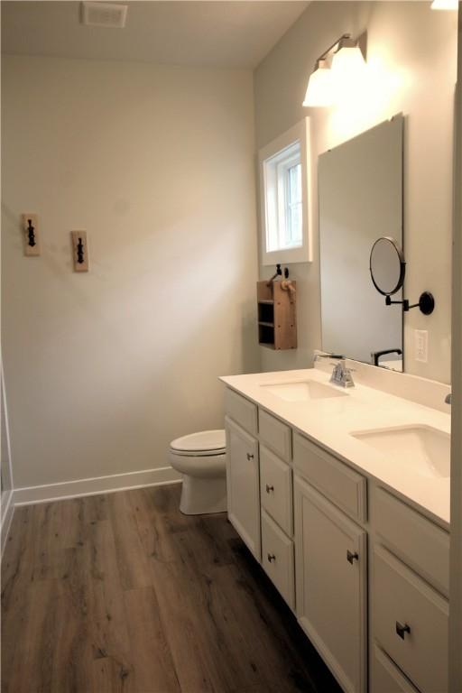 full bathroom featuring baseboards, a sink, wood finished floors, and toilet