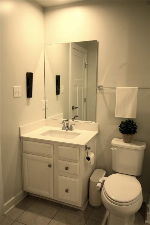 half bath featuring tile patterned floors, vanity, and toilet