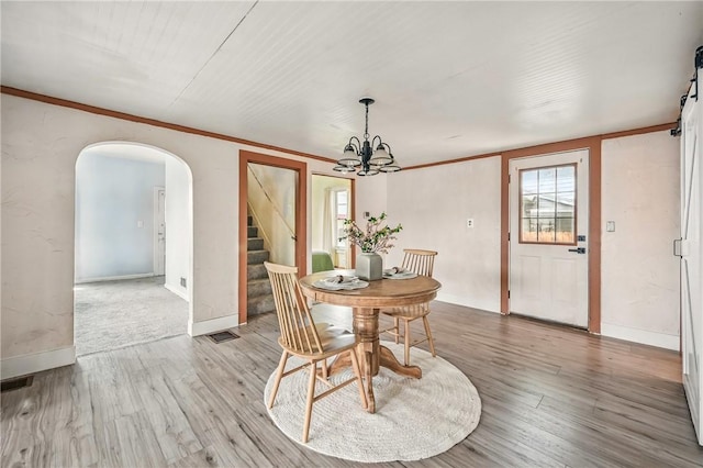 dining room with crown molding, arched walkways, wood finished floors, and stairway