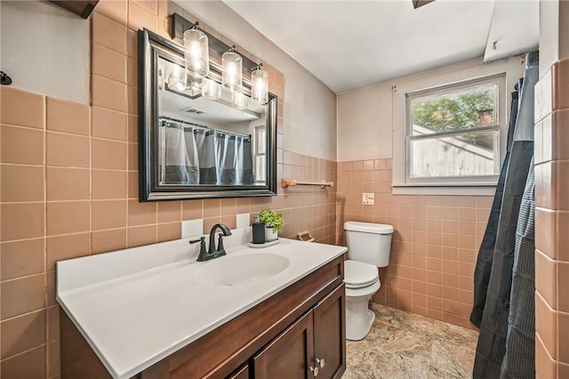 bathroom featuring vanity, toilet, and tile walls
