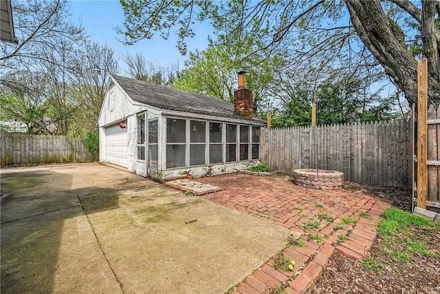 exterior space featuring a sunroom, a fenced backyard, and a detached garage