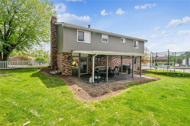 1 Fitch Ln, Mount Pleasant Twp Wml, PA 15601 - back of house featuring a chimney, a trampoline, a lawn, a patio area, and a fenced backyard