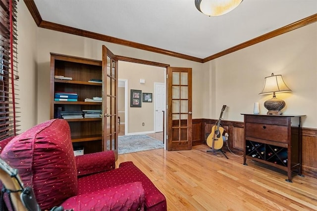 sitting room featuring a wainscoted wall, french doors, and wood finished floors