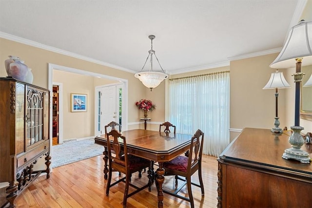 dining room featuring baseboards, visible vents, ornamental molding, and light wood finished floors