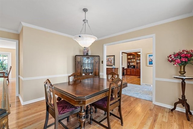 dining area with crown molding, baseboards, and light wood finished floors