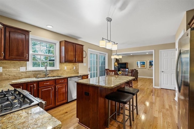 kitchen with backsplash, a kitchen island, a kitchen bar, appliances with stainless steel finishes, and a sink