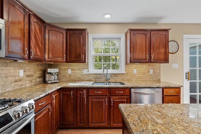 kitchen featuring a sink, appliances with stainless steel finishes, light stone countertops, and backsplash