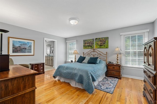 bedroom featuring connected bathroom, baseboards, and light wood-style flooring