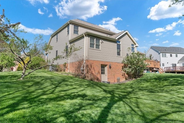 rear view of house featuring brick siding, a yard, and a deck