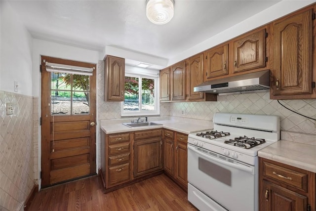 kitchen featuring a sink, under cabinet range hood, dark wood-style floors, and white gas stove